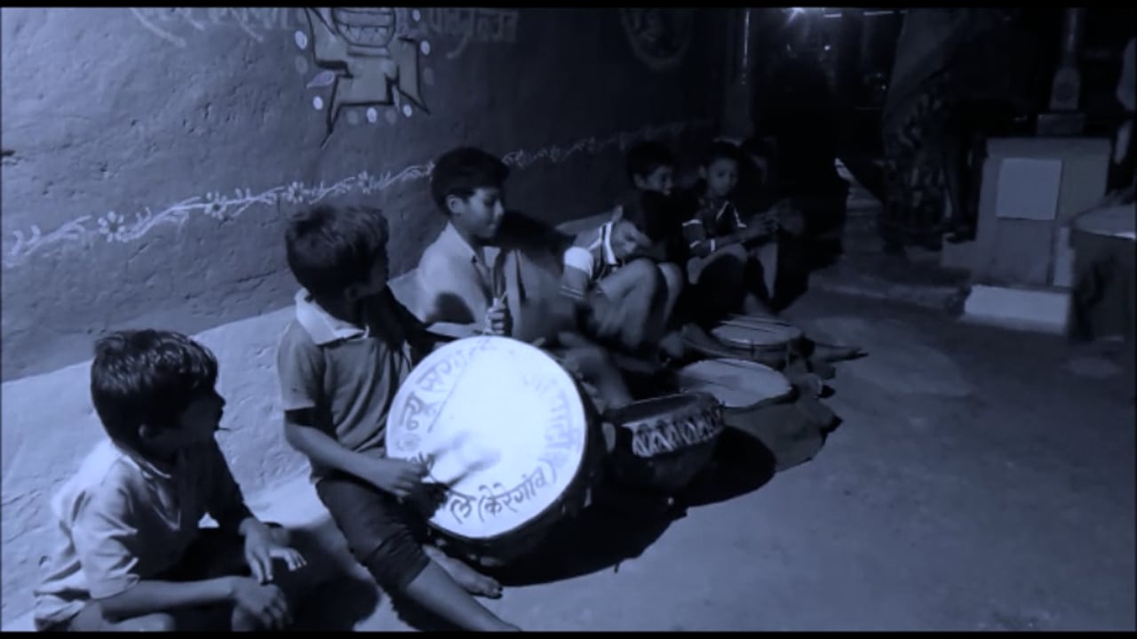 Still from Chinhari: The Young India &mdash; children seated together at night, one playing a drum